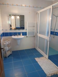 a blue and white bathroom with a sink and a shower at Casa FIGUEIRAS in Bensafrim
