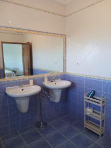 a blue tiled bathroom with two sinks and a mirror at Casa FIGUEIRAS in Bensafrim