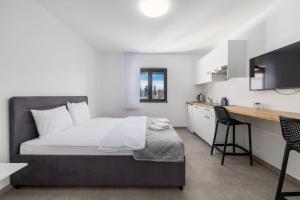 a bedroom with a bed and a desk and a kitchen at Apartments Rea in Krk