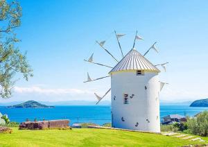 a white windmill sitting on top of a green field at 瓦の灯 in Takamatsu