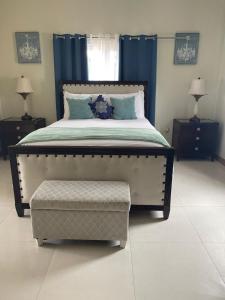 a bedroom with a large bed with blue curtains at The Full Maison at Ocho Rios in Ocho Rios +12 photos