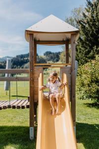 a little girl on a slide on a playground at Hofgut Wagrain Apartment & Lifestyle Resort in Wagrain +147 photos