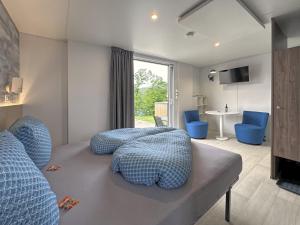 a bedroom with a bed and two blue chairs at Feriendorf Seeblick - Tiny Nr 11 in Neunburg vorm Wald