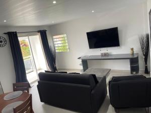 a living room with a couch and a flat screen tv at Relax Appart Hôtel in Kourou