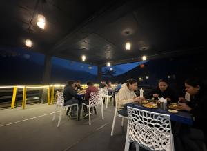a group of people sitting at tables in a restaurant at New Suraj Inn - Nestled near Hadimba Temple ! Rooftop Cafe ! Private Parking in Manāli