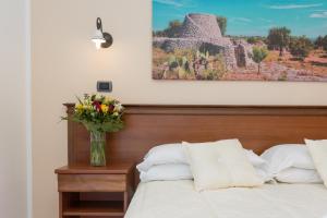 a bedroom with a bed with a vase of flowers on a table at Relais Casina Copini in Spongano +54 photos
