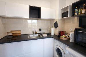 a kitchen with a sink and a microwave at L'Écrin Marguerite - Strasbourg-CMCO-Zénith-Espace Européen de l'Entreprise in Schiltigheim +8 photos