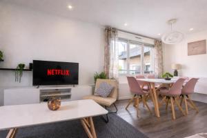 a living room with a tv and a table and chairs at L'Écrin Marguerite - Strasbourg-CMCO-Zénith-Espace Européen de l'Entreprise in Schiltigheim