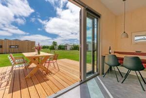 a patio with a wooden deck with a table and chairs at De Lepelaar - Ecohuisjes Terschelling in Midsland