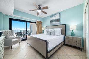 a bedroom with a bed and a chair and a balcony at The Palms West Unit 515 in Orange Beach