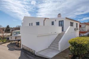 a white house with a white wall and stairs at Apartments Rea in Krk