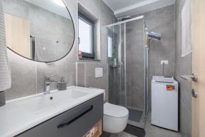 a bathroom with a sink and a toilet and a mirror at Apartments Rea in Krk +33 photos