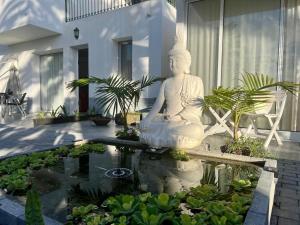a white statue sitting in a pond in a garden at Harmony Deluxe Accommodation in Água de Pau