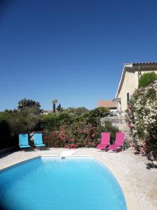a swimming pool with two chairs and a group at La Maison d'hôtes Antaram in Nyons