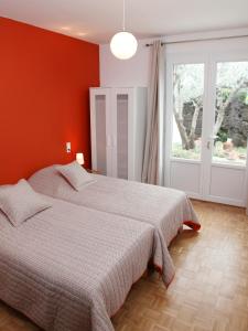 a bedroom with a bed with an orange wall at La Maison d'hôtes Antaram in Nyons