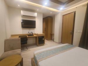 a hotel room with a bed and a desk with a television at Hotel Vardaan Inn in Lucknow +24 photos