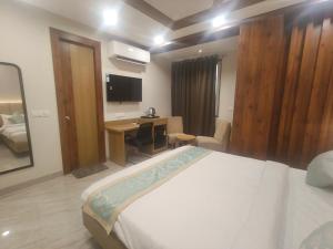 a bedroom with a bed and a desk and a television at Hotel Vardaan Inn in Lucknow