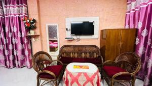 a room with a table and chairs and a tv at Marble Man Homestay in Agra