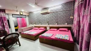 two beds in a room with pink sheets at Marble Man Homestay in Agra