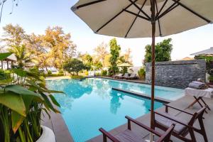 a swimming pool with two chairs and an umbrella at Naiya Sea Resort in Sihanoukville