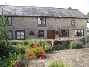 a stone house with flowers in front of it at The Old Barn in Rhoose