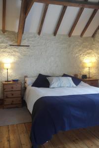 a bedroom with a bed and a stone wall at The Old Barn in Rhoose