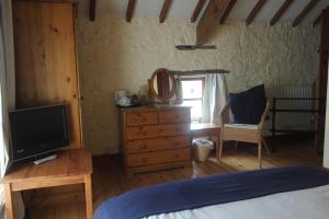 a bedroom with a bed and a dresser with a television at The Old Barn in Rhoose