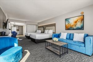 a hotel room with a blue couch and a bed at Nautilus Inn - Daytona Beach in Daytona Beach