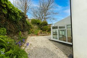 a house with a window and a gravel driveway at Waterwitch Cottage in Newquay