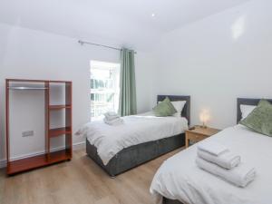 a bedroom with two beds and a mirror at Gate House in Llangefni