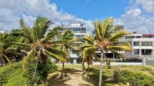 a group of palm trees in front of a building at Restinga 305- Flat vista mar no Bessa - ASKA in João Pessoa