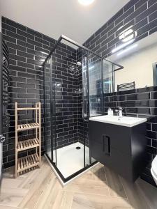 a black bathroom with a shower and a sink at Gudelių Kempingas Camp in Gudeliai