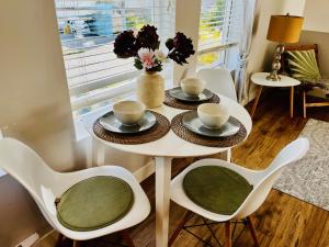 ein weißer Tisch mit zwei Stühlen und einer Vase mit Blumen in der Unterkunft Modern Maple Flat in Maple Ridge District Municipality