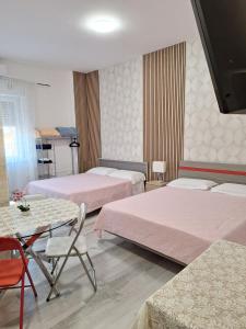 a bedroom with two beds and a table and chairs at Giada Rooms appartments in Peschiera del Garda