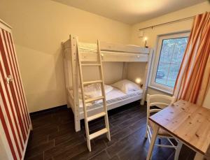 a room with two bunk beds and a table and a desk at Wellenläufer Breege in Breege