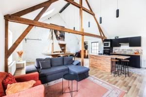 a living room with a blue couch and a kitchen at Large bright apartment in Lessines