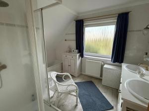 a bathroom with a chair and a sink and a mirror at Ferienhaus Villa Deichfürst in Dorum-Neufeld +30 photos