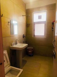a bathroom with a sink and a toilet and a window at Red Brick Home stay in Kulu