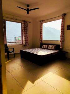 a bedroom with a bed and two large windows at Red Brick Home stay in Kulu