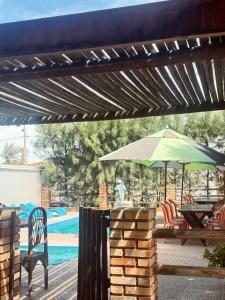 a patio with a green umbrella next to a pool at Pousada e Chalés mar e sol in Manibu