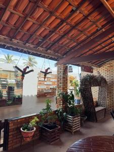 a patio with plants and birds hanging from a roof at Pousada e Chalés mar e sol in Manibu