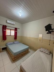a bedroom with two beds and a television in it at Pousada e Chalés mar e sol in Manibu +19 photos