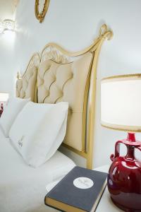 a bed with a red vase and a book on a table at B&B Magnolia Centro Storico Grottaglie in Grottaglie +92 photos