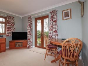a living room with a table and chairs and a television at Honeysuckle Rise in Looe