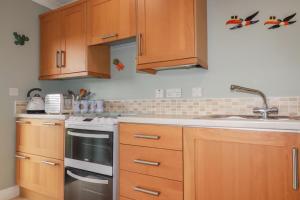 a kitchen with wooden cabinets and a sink at Honeysuckle Rise in Looe