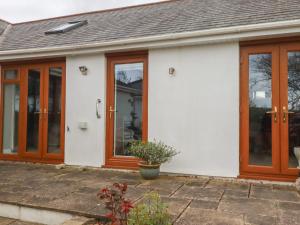 a white house with wooden doors and a potted plant at Honeysuckle Rise in Looe