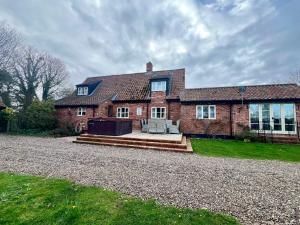 a large brick house with a gravel driveway at Locks Lane Cottage in Geldeston