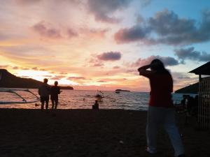 a group of people standing on the beach watching the sunset at Llave transient 2 in Nasugbu