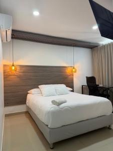 a bedroom with a large white bed with two lights at Hotel Sun Suite in Barranquilla