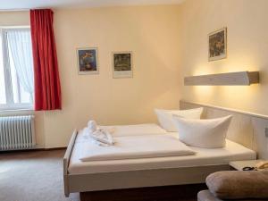 a bedroom with a white bed with a red curtain at Hotel Restaurant Bären in Weingarten